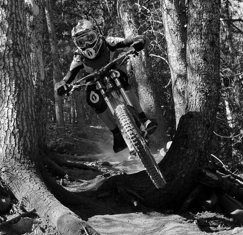 Downhill racer dropping through a forest section of the course