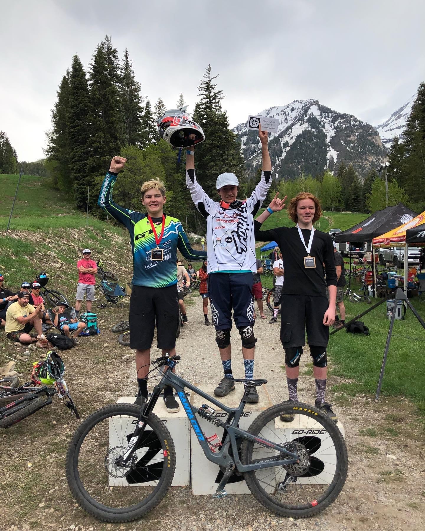 Young racers on the podium in Salamander Racing kit with Mount Timpanogos behind at a Utah Gravity Series downhill event